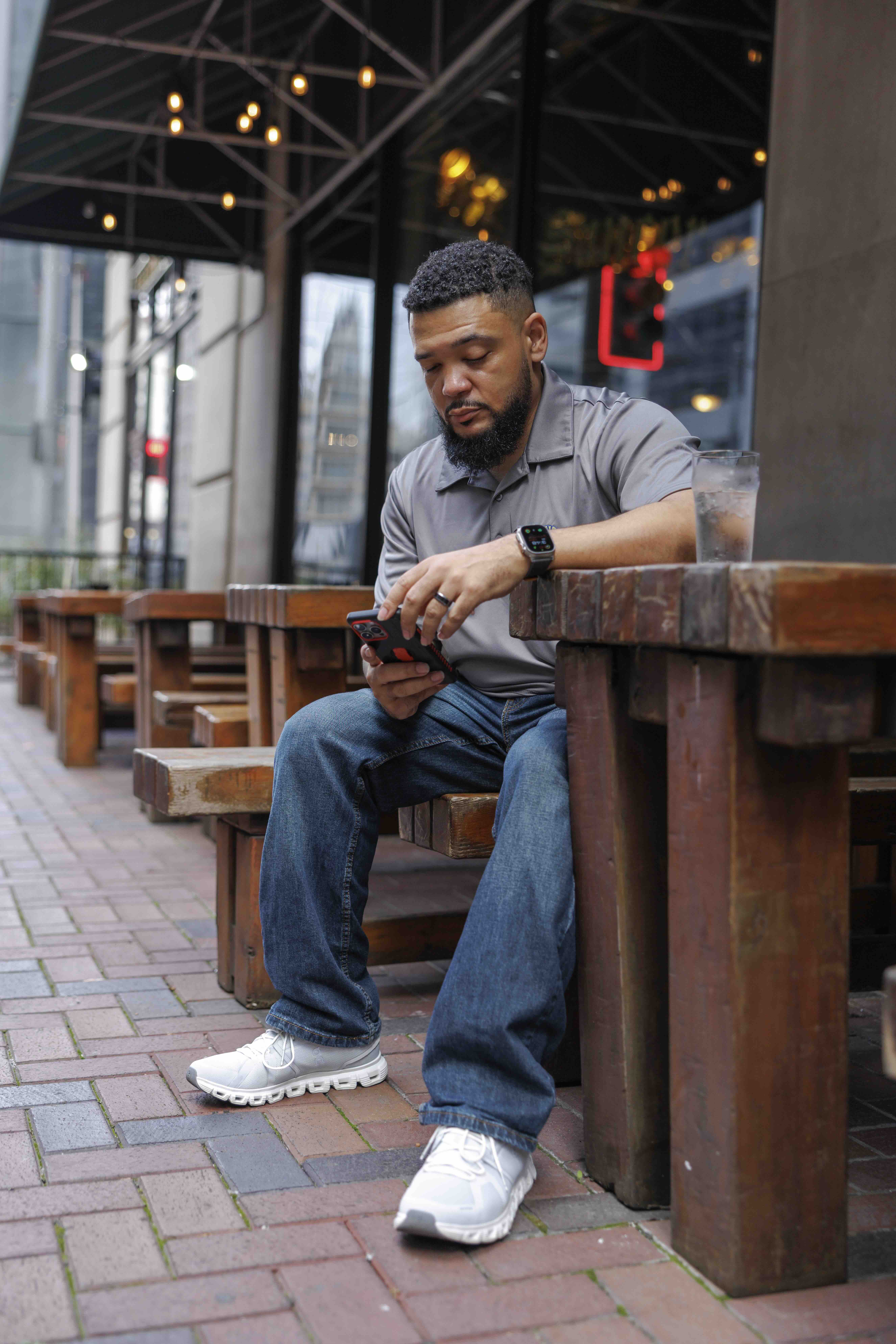 VNCC founder looking down at his iphone seated in front of a restaurant out doors